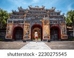 Small photo of Young woman touring the interior of the ancient imperial city of Hue, Vietnam. Ancient stone gate of the imperial city of Hue, Vietnam. Happy tourist in Vietnam. Old gate of the imperial city of Hue
