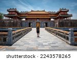 Small photo of Hue, Hue, Vietnam, 06-13-2022. Young man at the gates of the imperial city of Hue, Vietnam. Tourist in Hue, Vietnam. Famous entrance to the imperial city of Vietnam
