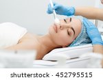 Model lying on couch with closed eyes. Hand in blue glove touching patient's face with brush. Cosmetological clinic. Healthcare, clinic, cosmetology