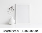 Small photo of White desk with photo frame and minimal round vase with a decorative twig against white wall.