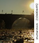 Small photo of autumn sunset historic bridge with flouting leaves
