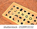 Small photo of DJANGO word text from wooden cube block letters on braided rattan mats background.