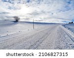 Roadway in winter with snow, gravel, gravel stones and snow poles