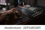 Small photo of Audio engineer uses mixing console, remote control for adjusting sound, audio mixer. Musician changes the volume level, creates song with modern equipment. Sound recording studio. Music production.