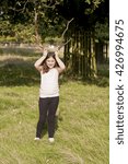 Small photo of Playing Pretend. A young girl is larking around in a park, playing with some dead branches pretending they are antlers. Girls, just like boys, love to muck around and play.
