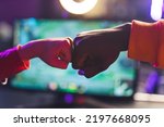 Small photo of Close-up shot of two online game players celebrating victory in tournament giving eachother a fist bump in front of the screen. Blurred background. Horizontal shot . High quality photo