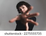 Blurred foreground. Woman reaching forward with her hand. Medium shot. Grey background. High quality photo