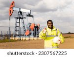 Small photo of Successful crude oil production. Portrait of hardworking oil field worker holding thumbs up.