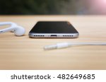 Smart phone on the table without audio connectors. No Headphone jacks nor microphone jacks 3.5 mm. Stereo speakers. Shallow depth of field.  