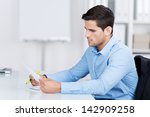 Businessman reading a document while sitting at his desk in the office looking at it with a serious expression