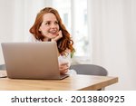 Small photo of Mesmerised or infatuated young woman staring off to the side with wide eyes and parted lips as she sits behind a laptop computer in a high key office