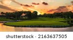 Small photo of Panoramic view of beautiful golf course with pines at sunset. Golf field with fairway, lake and pine-trees