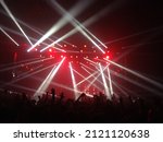 Small photo of White strobe lights at a gig. A crowd of fans raising their hands at a live concert. A bunch of fans in front of strobe lights and red lights above the stage