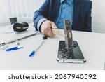 Small photo of embittered businessman hits a smartphone with a hammer in workplace. Unsuccessful business negotiations concept. failure of transaction.