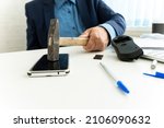 Small photo of embittered businessman hits a smartphone with a hammer in workplace. Unsuccessful business negotiations concept. failure of the transaction.
