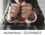 Small photo of handcuffed hand is strapped inside interrogation room. the concept of arrest and incarceration. A prisoner in prison. interrogation in prison. criminal is being interrogated. conducting interrogations