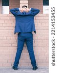 Small photo of the arrested man in a business suit stands against a brick wall with his hands raised up. Arrest and search of a corrupt deputy. Businessman under suspicion concept. Selective focus
