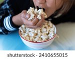 Small photo of Close-up portrait of nice cute attractive cheerful positive girl grasping pop-corn in hand. Salty popcorn in mouth. Junk food and children.