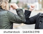 Elbow bump. New novel greeting to avoid the spread of coronavirus. Two women friends meet in a British street with bare hands. Instead of greeting with a hug or handshake, they bump elbows instead.