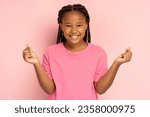 Small photo of Positive African girl in pink t shirt gesturing showing heart from fingers, k pop culture, isolated on pink background, mockup. Young modern child with toothy smile looking at camera