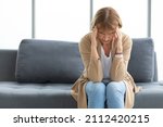 senior woman have a headache on a sofa