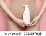 Small photo of Woman Holds White Bottle Of Hygiene Product, Washing, Cleansing Intimate Gel, Foam. Female Wears Beige Body On Pink Background. Mockup Branding Dispenser, Daily Body Care. Horizontal Plane, Closeup
