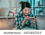 Small photo of asian woman watching movie on mobile phone at home in night. young girl having fun stay up late enjoy comedy show film funny on cellphone sitting on couch. happy female laughing using technology.