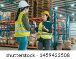 Small photo of Happy female manager and worker standing together in warehouse office. two women staff in storehouse discussing cooperation. young girls employees wearing hard hats and safety vest in stockroom.