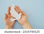 Small photo of White paper origami bird on blue background. World Day of Peace. Day Against Humiliation. International Day Of Human Fraternity. International Day of Living Together in Peace