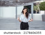 Happy Arab woman outdoor with business background. Arabian or Indian businesswoman thumbs up looking excited