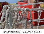 Small photo of Texture of white and strong gangway net made of nylon fiber, as a grip and safety when crossing the ship's gangway. Safety net installed between the pier and the ship as a background or backdrop