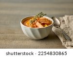 bowl of homemade salmon and tomato soup on wooden kitchen table