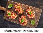 toasted bread with chopped tomatoes on wooden cutting board, top view