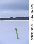 Small photo of Green navigational spar buoy on a frozen lake in Hollola, Finland