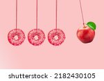 Small photo of Newton's cradle from doughnuts. Collision balls made from donuts and red apple. Healthy diet concept. Diabetes concept.