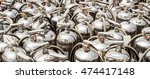 Small photo of Many depressurized discarded old silver fire extinguishers with inspection tags stand abandoned in the sun.