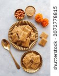 Small photo of Indian makar sankranti festival food or sweets. Tilgul in a small brass plate. Tilgul is made out of sesame seeds, peanuts, ghee and jaggery. Til gul chikki or sesame candy. Copy Space. Winter food.