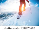 A man in snowshoes in the mountains in the winter. A climber with trekking sticks walks through the snow. Winter ascent. Beautiful sky with clouds.