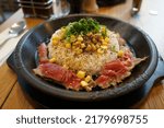 Pepper rice with red meat steak on a hot plate with sweet corn and spring onion.