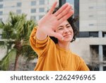 Front view of a shy latin girl hiding from the camera. Happy hispanic young woman smiling and covering her face with her hand palm. High quality photo