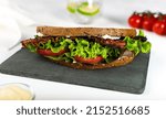 Small photo of classic btl sandwich on on a white table with tomatoes, mayonnaise, with a glass of water