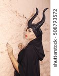 Small photo of Maleficent demonic - starring. Beautiful woman from a fairytale with hair horns outdoor. Beautiful girl with horns dressed up as devil. Woman with makeup, nail polish. Fantasy. Halloween concept.