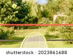 Small photo of Casual badminton in garden concept with shuttlecock flying over the net and racket ready to fend off