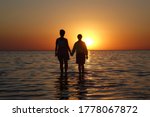 two people walk on water at sunset          