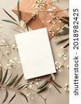 Small photo of Invitation or greeting card mockup with craft paper envelope, eucalyptus and gypsophila twigs. Card mockup with copy space on beige background.