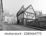 tudor house misty foggy morning black and white cobbled streets atmospheric lincoln steep hill