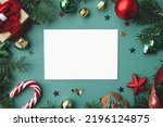 Christmas card mock up. Modern greeting card flat lay with stylish christmas decorations and fir branches on green background. Empty postcard template with space for text. Merry Christmas!