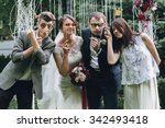 elegant stylish happy guests and bride and groom having funny photos on the background of arch, photo booth