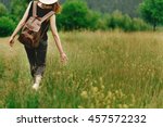 stylish hipster woman walking in grass and holding  in hand herb  wildflowers  in summer mountains, travel concept, peaceful relaxing moment. happy earth day