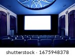 Small photo of Cinema theater screen in front of seat rows in movie theater showing white screen projected from cinematograph. The cinema theater is decorated in classical style for luxury feeling of movie watching.